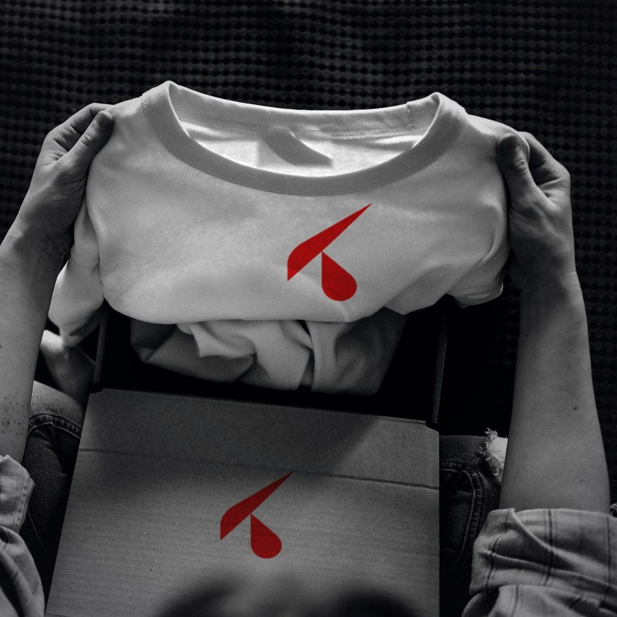 Mani che tolgono dalla scatola una t-shirt bianca stampata con il logo