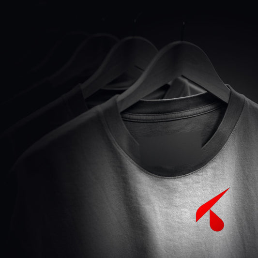 Fila di t-shirt identiche su grucce di legno nel buio, la prima illuminata con il logo K rosso stampato sul cuore