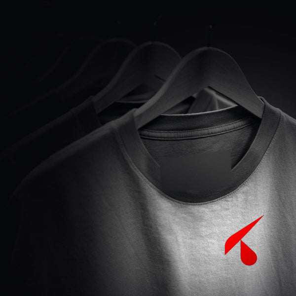 Fila di t-shirt identiche su grucce di legno nel buio, la prima illuminata con il logo K rosso stampato sul cuore